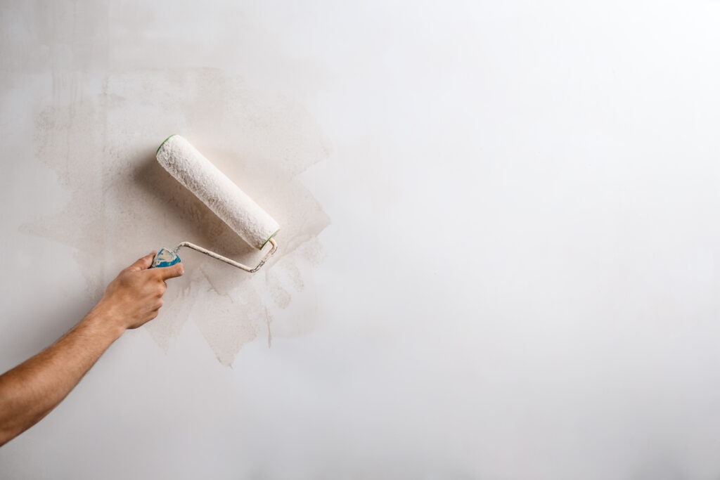 Close up photo of hand painting wall with roller in white color. Copy space.